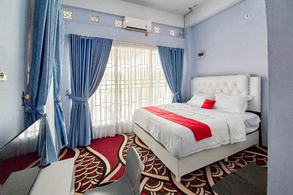 a bedroom with a bed with blue walls and a window at RedDoorz Syariah at Masrun Homestay Bangkinang in Bangkinang