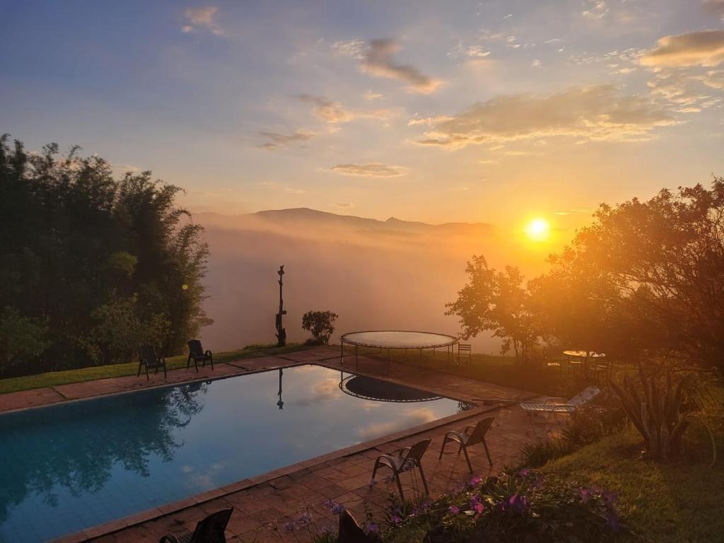 a swimming pool with a sunset in the background at Pousada Suçuarana in Itabirito