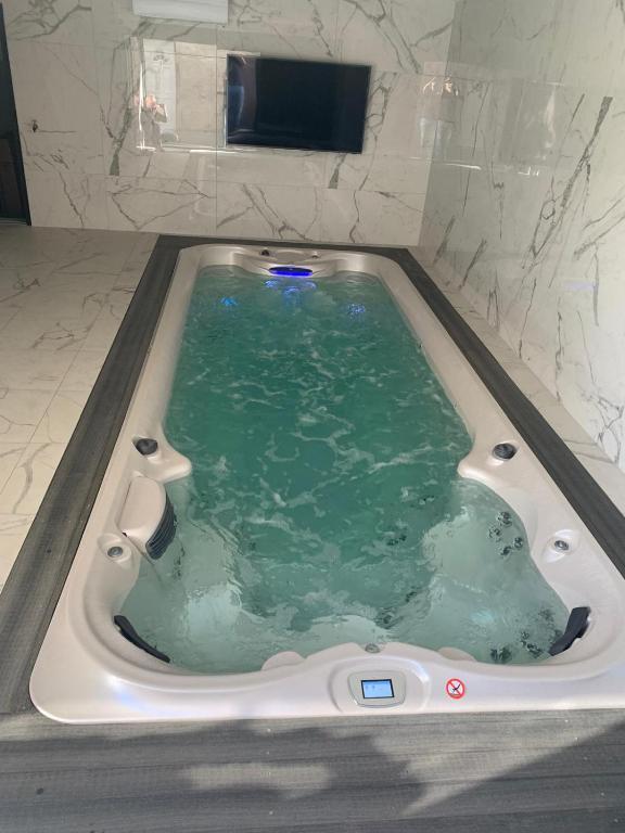 La salle de bains est pourvue d'une baignoire remplie d'eau verte. dans l'établissement Grange&Lodge, à Chavelot