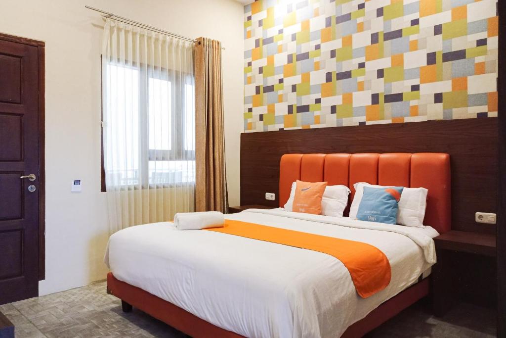 Un dormitorio con una cama grande con cabecero naranja. en Sans Hotel Grand Jitra Syariah Bengkulu, en Bengkulu