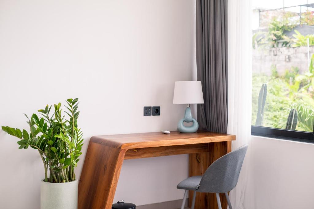 a desk with a lamp and a chair next to a window at Sunny Village Berawa in Canggu