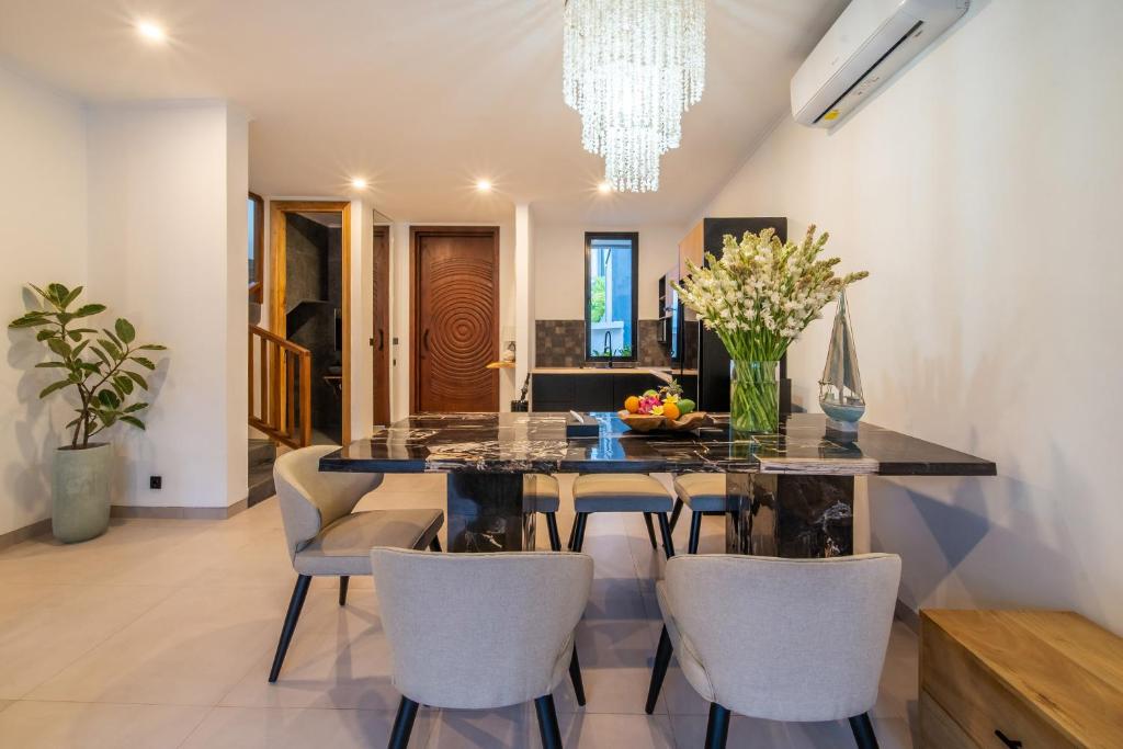 a dining room with a black table and chairs at Sunny Village Berawa in Canggu