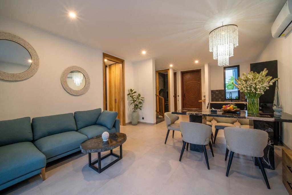 a living room with a blue couch and a table at Sunny Village Berawa in Canggu