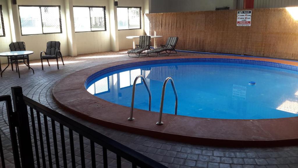 a swimming pool with a pool table and chairs at Herbert Valley Motel in Ingham