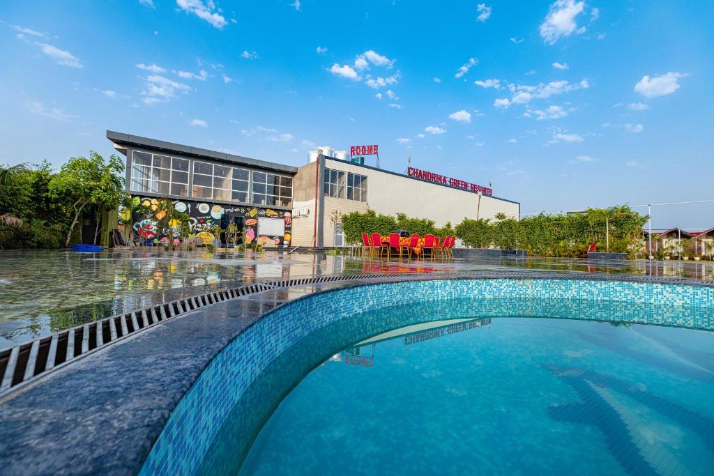 a swimming pool in front of a building at Chandrika Green Resort in Vrindāvan