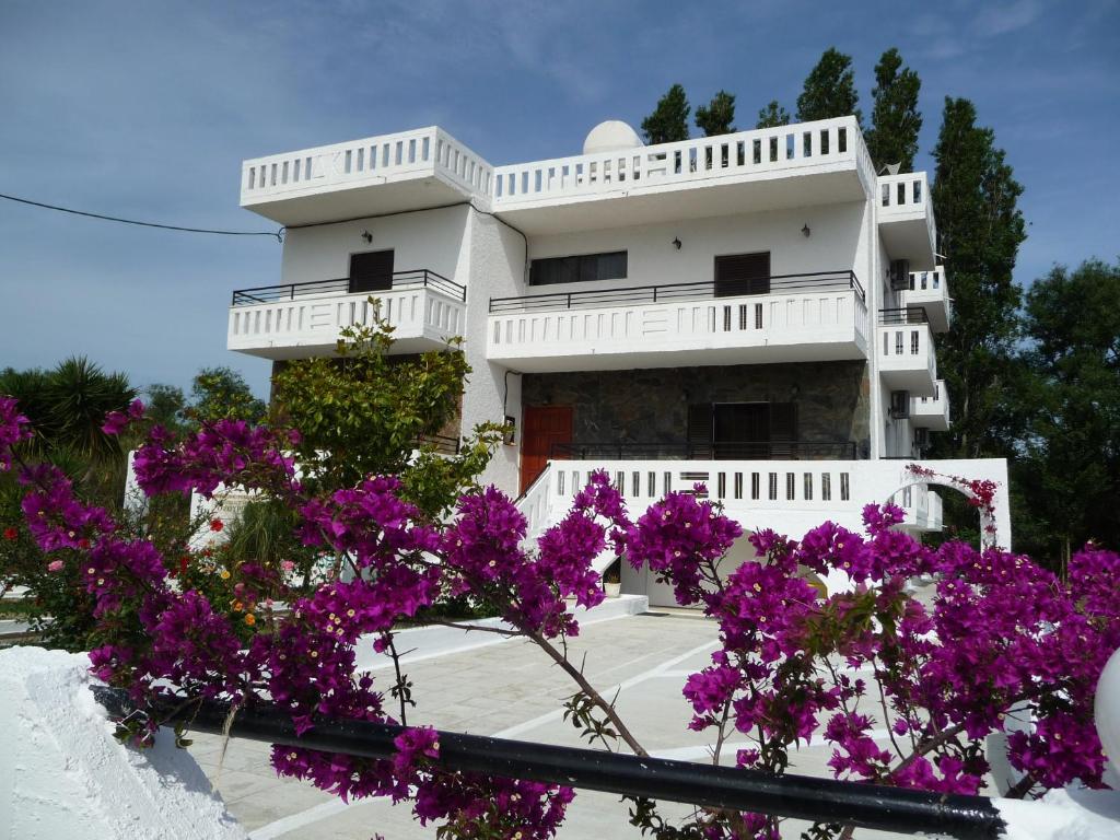 a white house with purple flowers in front of it at Zourpos Studios & Apartments in Kalyves