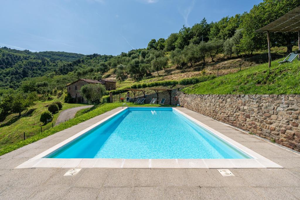 a swimming pool in front of a stone wall at Fattoria di Pietrabuona in Medicina