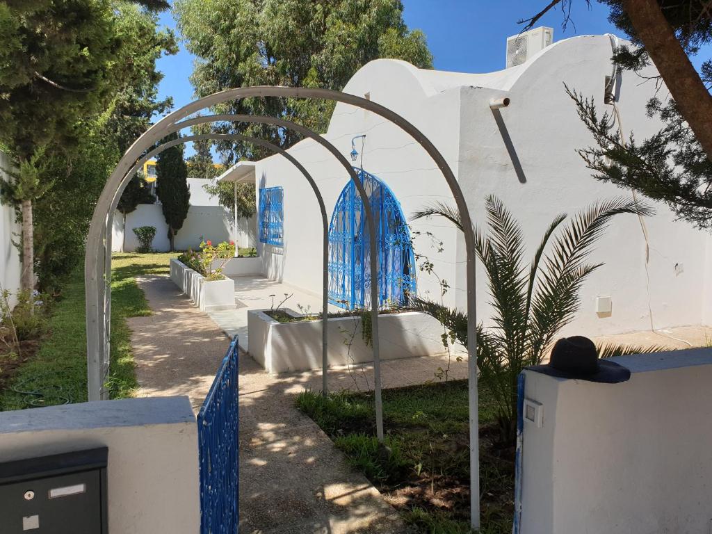 a gate to a white building with a blue object at Chelly Bungalow en bord de mer in Nabeul