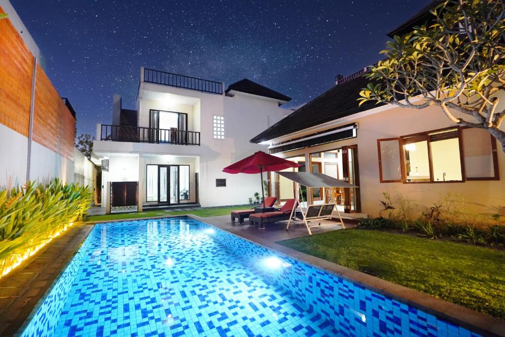 a swimming pool in front of a house at night at Mahabrahma Villa in Uluwatu