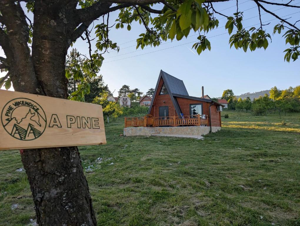 a pine sign on a tree in front of a house at AA Pine vikendica za izdavanje u srcu Zapadne Srbije in Nova Varoš