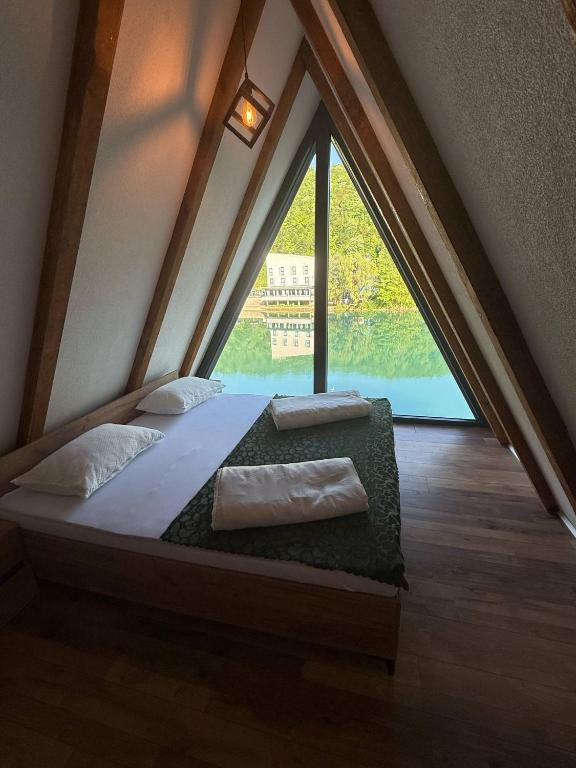 a bed in a room with a large window at Vikendica Hamza in Bihać