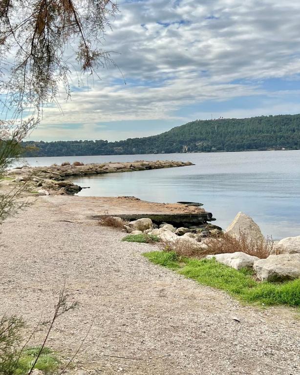 a beach with rocks and the water and trees at Au bord de la digue in Saint-Chamas
