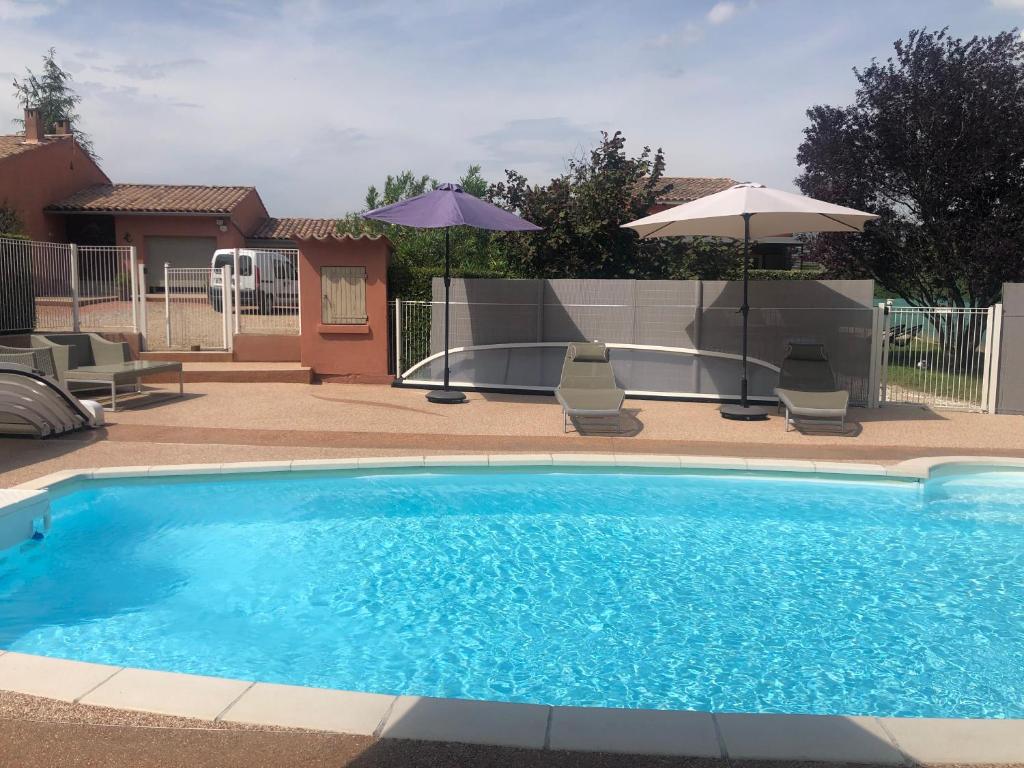 - une piscine avec 2 chaises longues et 2 parasols dans l'établissement VILLA AVEC PISCINE, à Roussillon