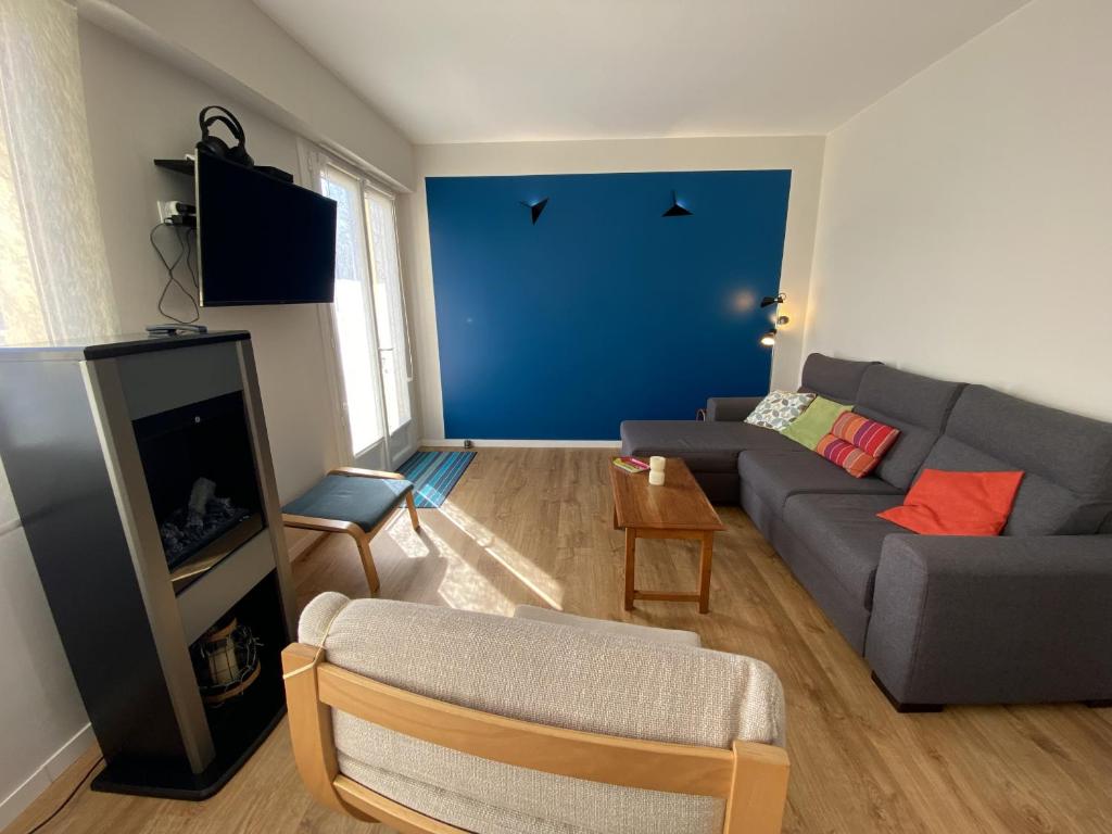 - un salon avec un canapé gris et un mur bleu dans l'établissement Appartement Le Leon, à La Rudelière