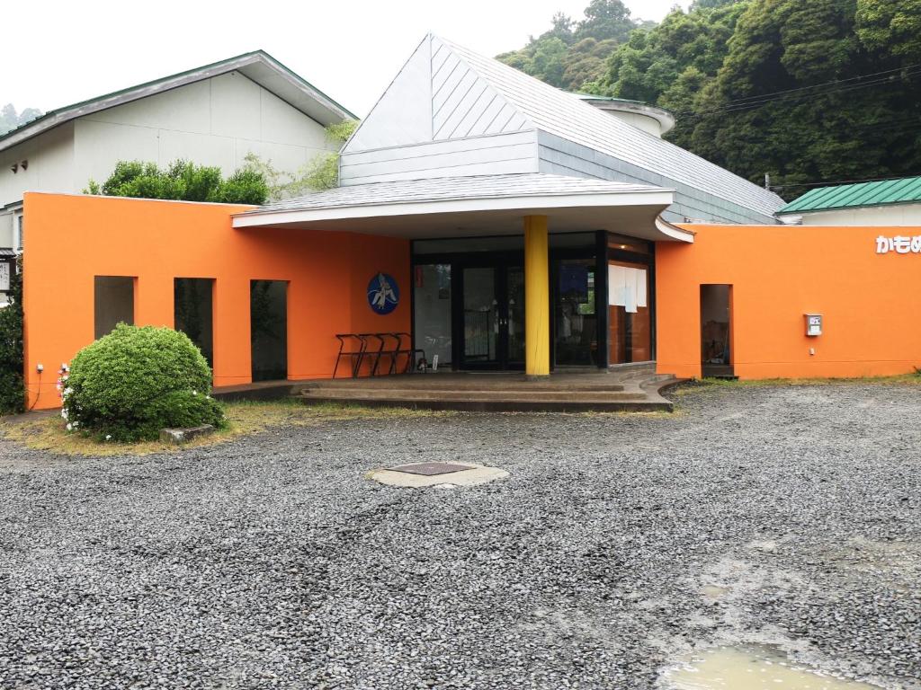 un edificio naranja y blanco con porche en Ryokan Kamomeso en Sado