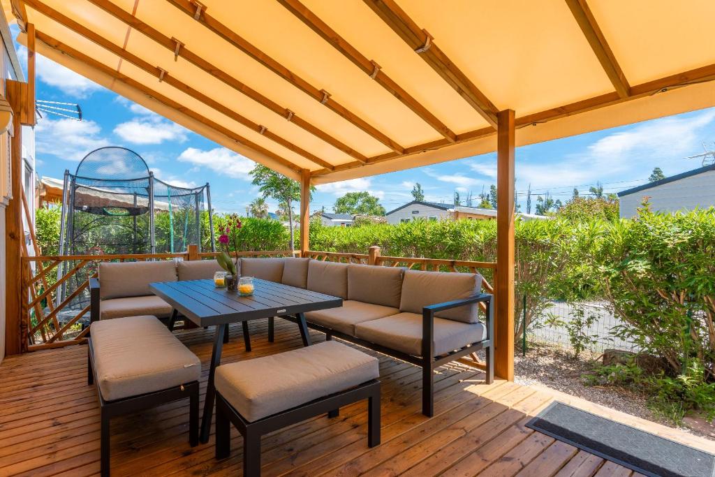 eine Terrasse mit Tisch und Stühlen auf einem Deck in der Unterkunft Le Mediterranéen in Fréjus