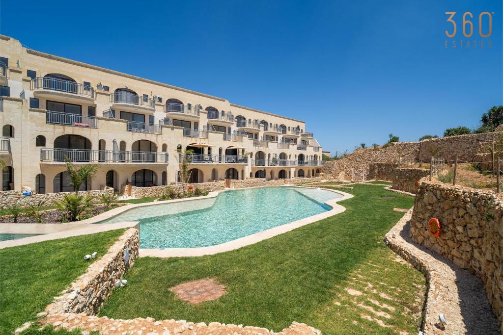 a swimming pool in front of a building at Serene Apt with Terrace & Pool & BBQ Access,Qala by 360 Estates in Qala