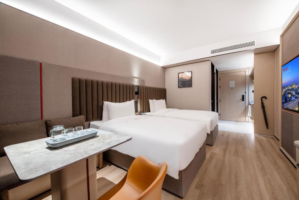a hotel room with a large bed and a desk at IntercityHotel Shanghai Hongqiao Airport - Free Minibar for First Night in Shanghai