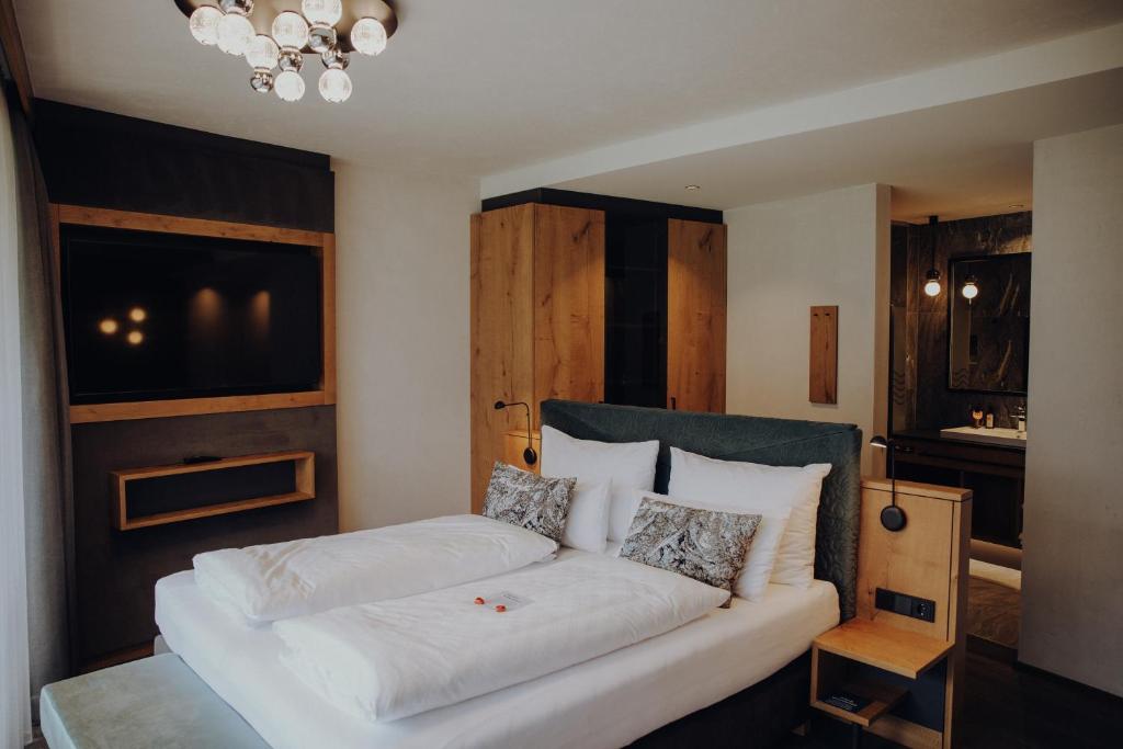 a bedroom with a couch with pillows and a tv at Hotel Wagnerhof in Pertisau