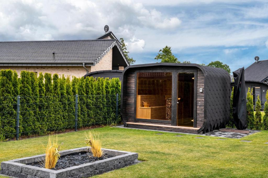 a black iguana house in a yard at Ferienhaus am See mit Sauna in Barßel