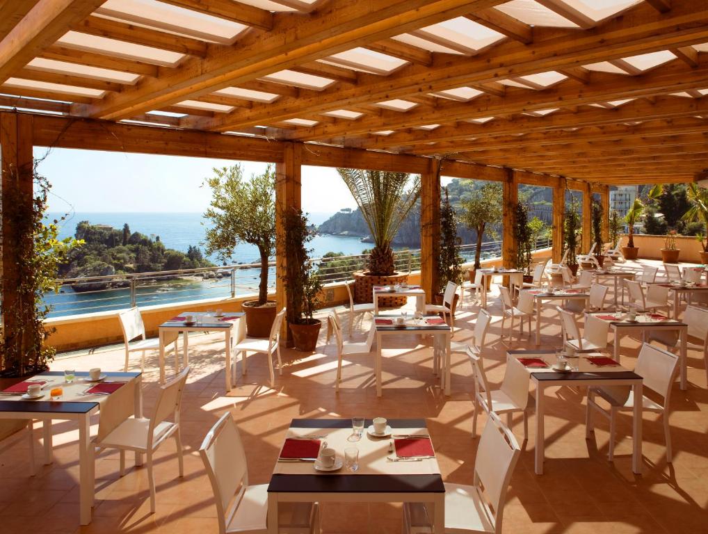 a restaurant with tables and chairs and a view of the ocean at Taormina Panoramic Hotel in Taormina