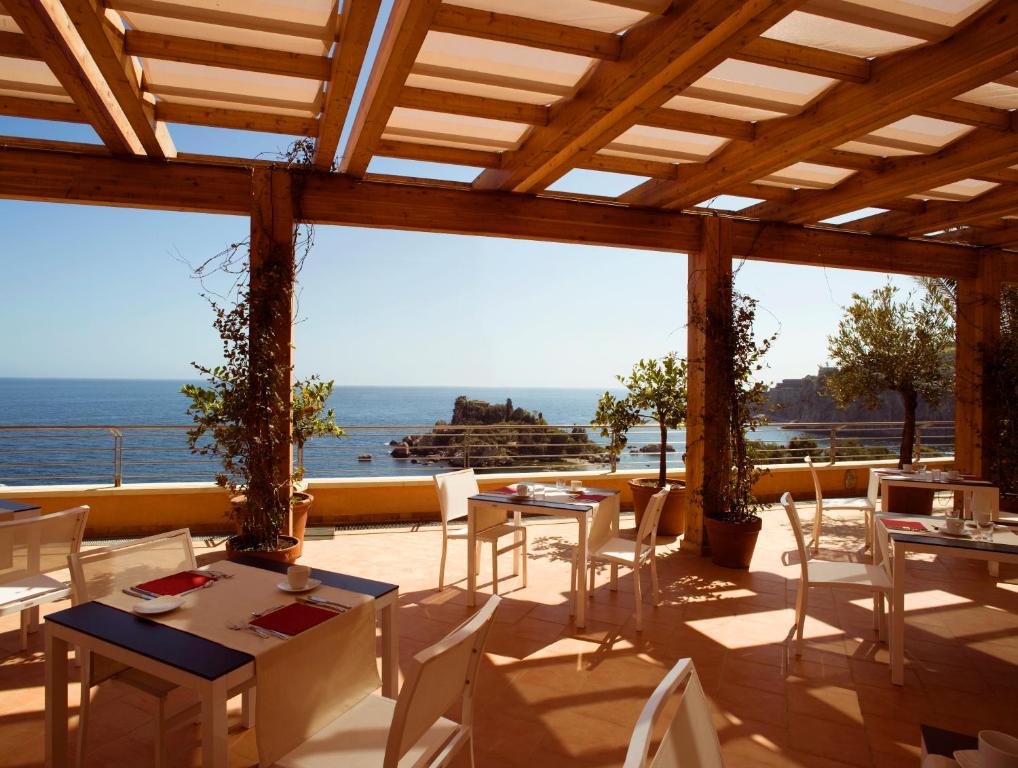 a patio with tables and chairs and a view of the ocean at Taormina Panoramic Hotel in Taormina