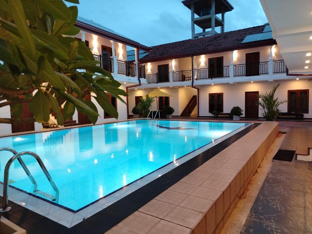 a swimming pool in front of a building at Grand Leisure Care & Wellness Resort in Negombo