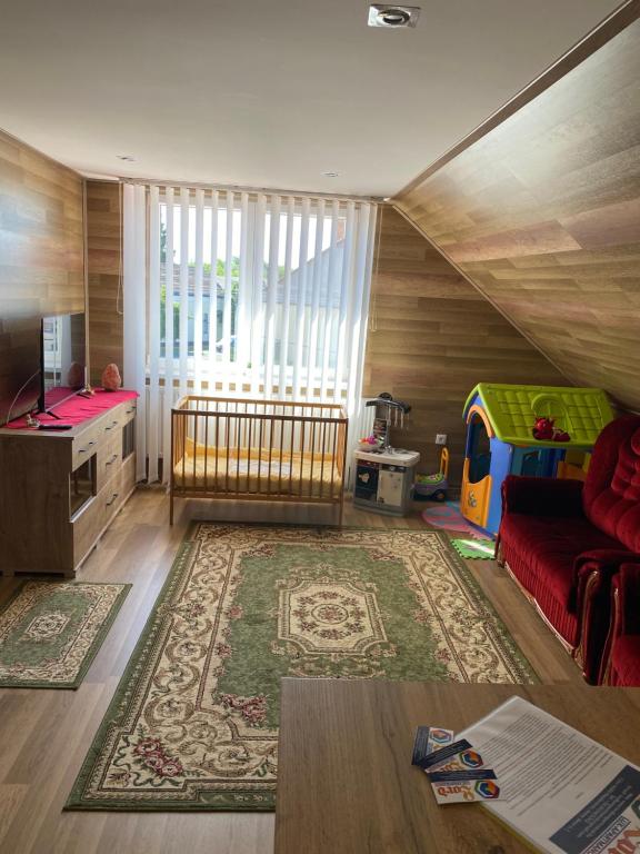 a living room with a red couch and a play area at LORD LUX Apartmanok in Hajdúnánás