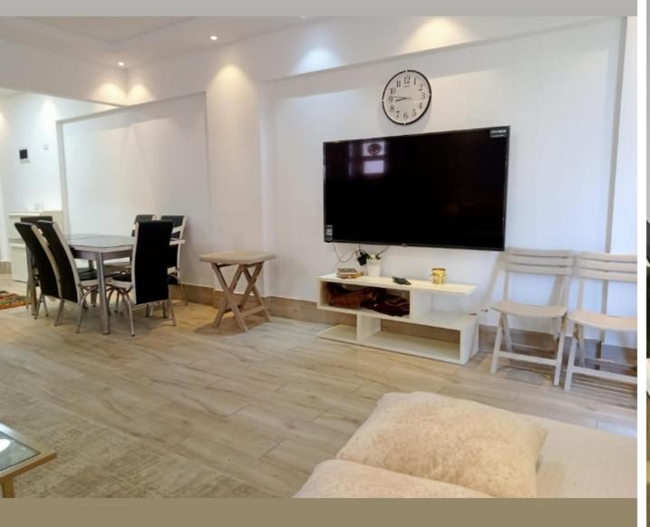 a living room with a large television and a table and chairs at مارينا دلتا in Al Ḩammād