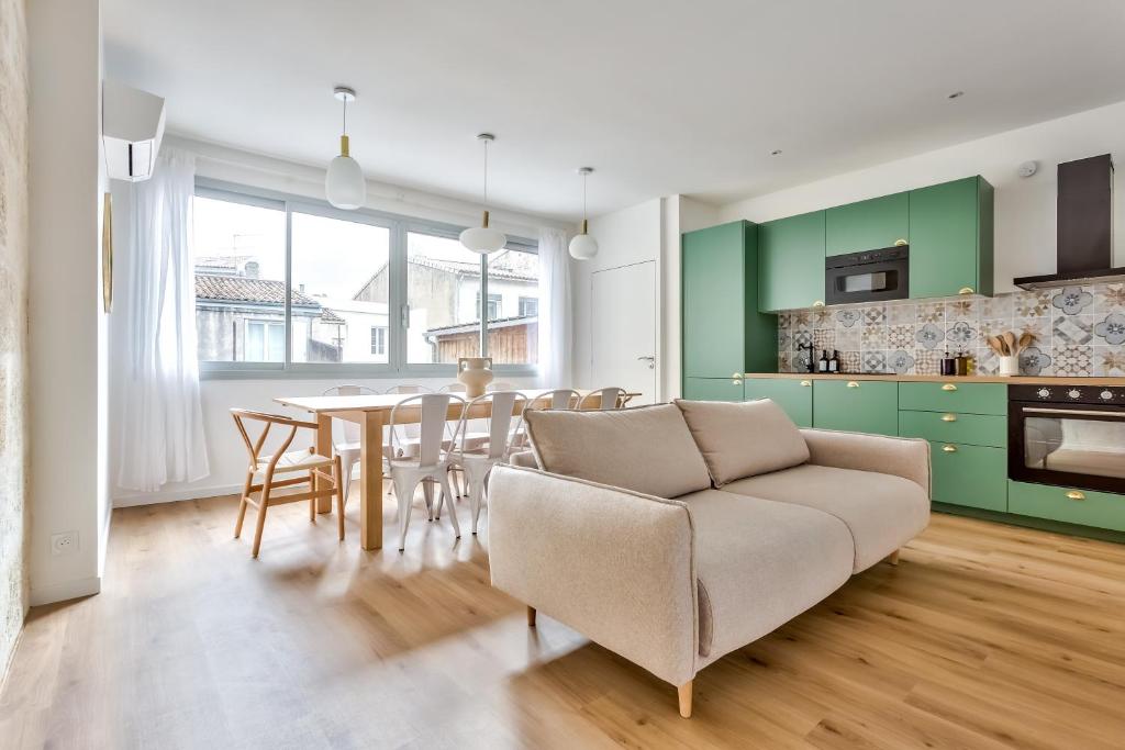 uma sala de estar com um sofá e uma mesa com cadeiras em Nocnoc - Le Balcon de l'Oli 99m2 em Bordéus