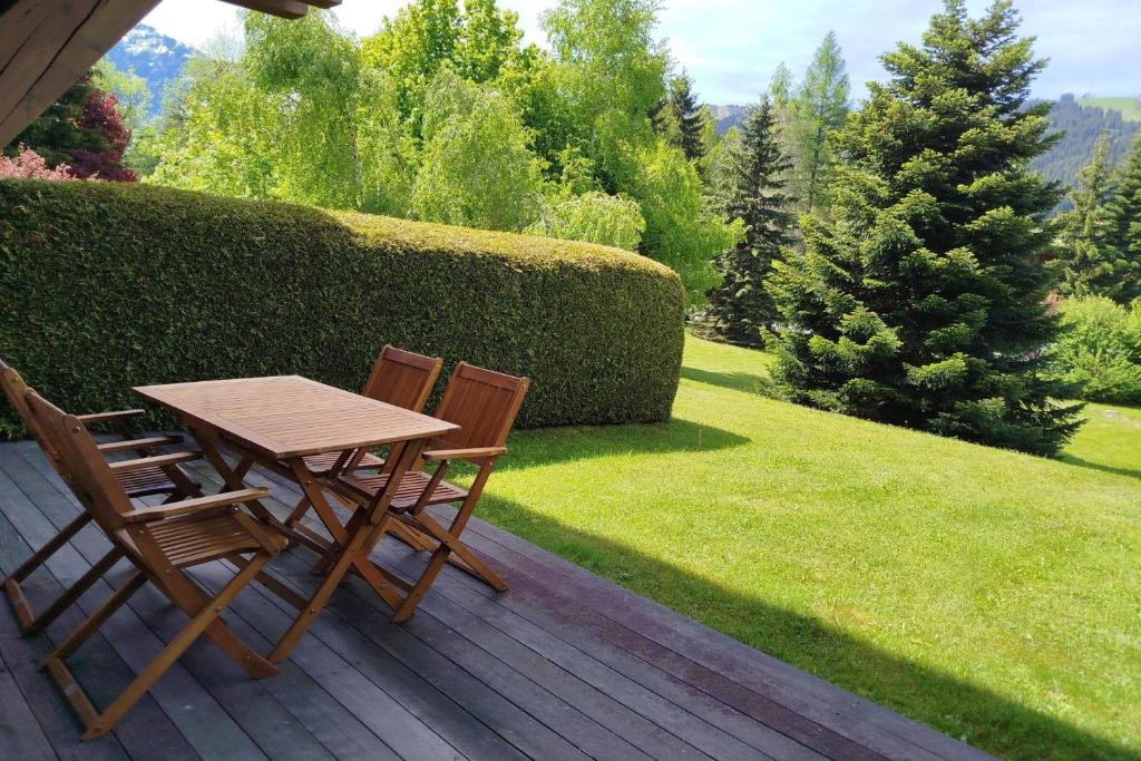 une table en bois et deux chaises assises sur une terrasse dans l'établissement Apartment with garden on the snow front, à Megève