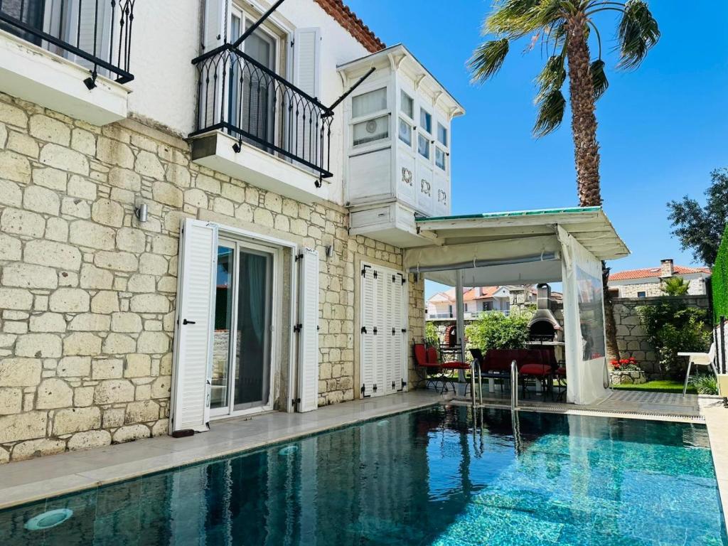 a house with a swimming pool in front of a building at Evalacati-Villa Palma-Central villa with private pool and garden in Çeşme