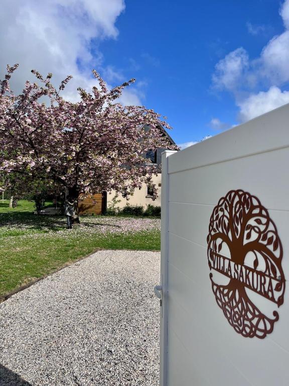 une clôture blanche avec une pancarte à côté d'un arbre dans l'établissement Villa Sakura, à Beaumont-en-Auge
