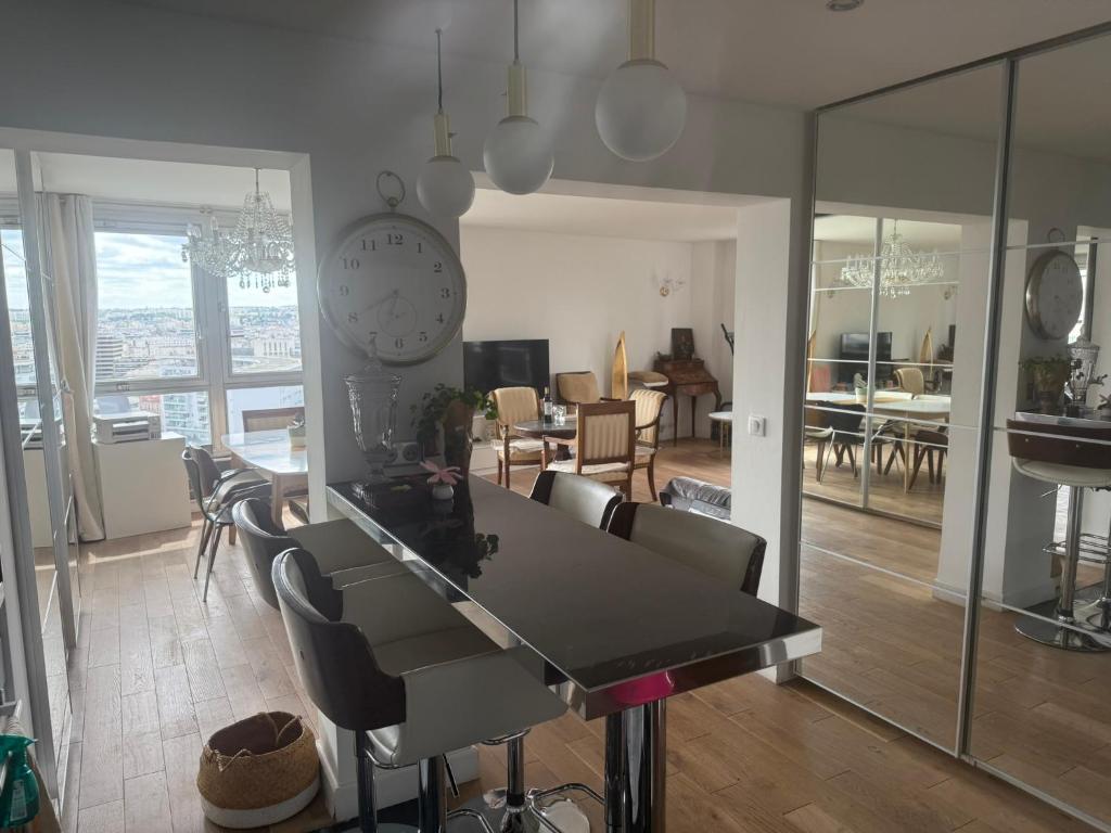 une cuisine et un salon avec une table et des chaises dans l'établissement Vue, espace & confort Appartement 2 chambres avec terrasse & parking, aux portes de Paris, à Puteaux