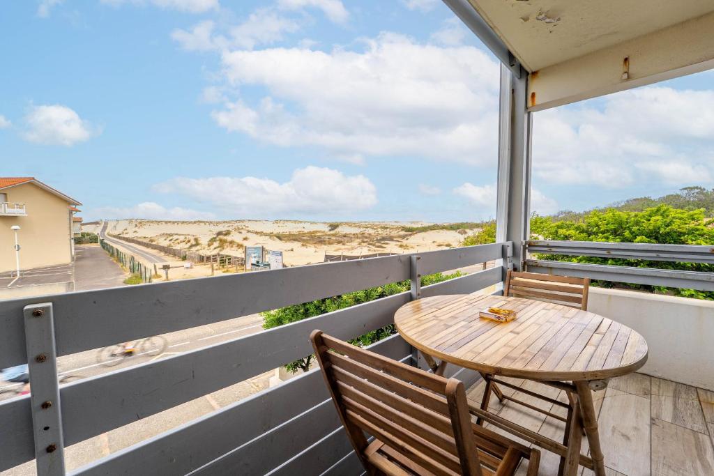 un tavolo e sedie su un balcone con vista sulla spiaggia di Appartement au pied des dunes avec vue a Biscarrosse