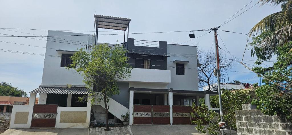 a white building with a balcony on top of it at SHIs Spandha Apartments Near Coimbatore Airport in Coimbatore