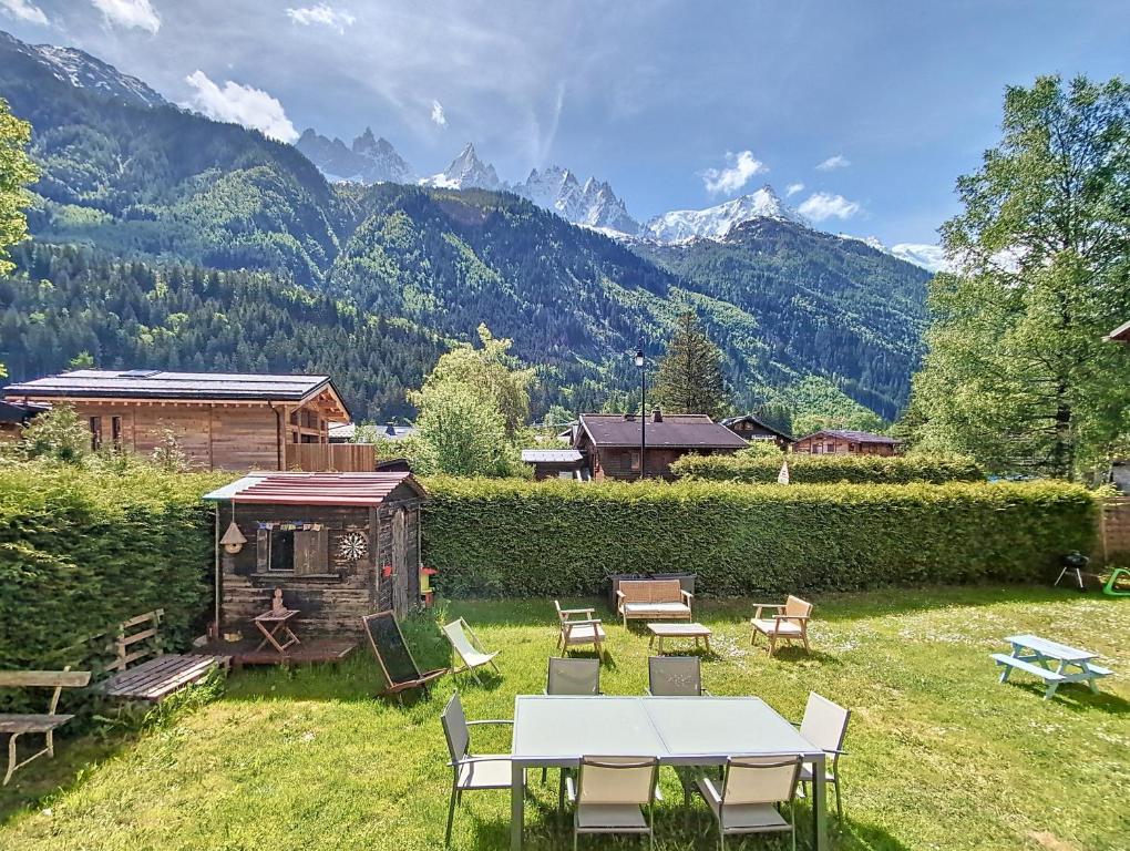 une cour arrière avec une table, des chaises et des montagnes dans l'établissement Le cosy refuge, à Chamonix-Mont-Blanc
