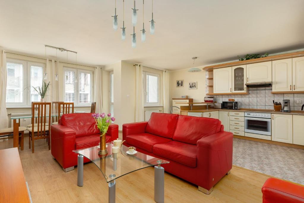 a living room with two red chairs and a table at Central Port Giełdowa Apartment by Solarento in Kołobrzeg