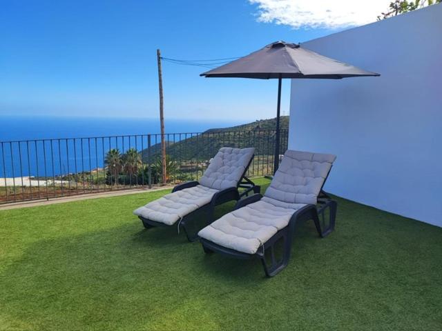 PuntallanaにあるCasa de campo con vistas al marの芝生の上に椅子2脚と傘が置かれている
