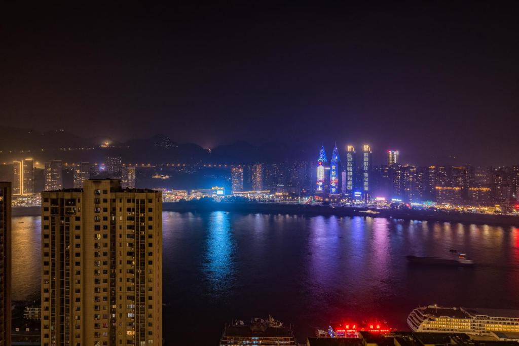 a view of a city at night with the water at 云深处江景公寓 in Chongqing