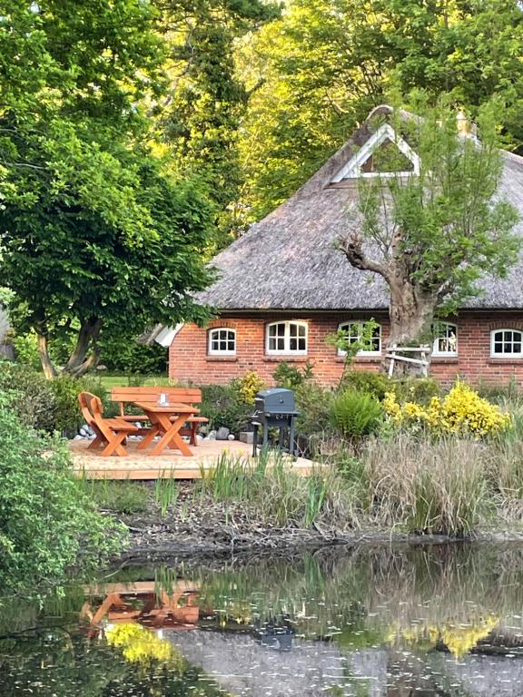 Un edificio con una mesa de picnic junto a un estanque. en Reetdachhaus am See Ostfriesland, en Leezdorf