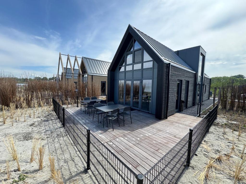 a black house on a wooden deck with a table at Enkhuizer Strand BeachHouse Deck Acht mit Zaun Nr 408 in Enkhuizen
