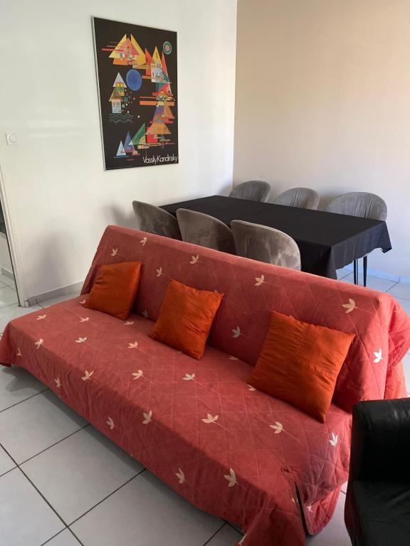 un canapé rouge avec des coussins sur un sol avec des chaises dans l'établissement Location saisonnière Avignon, à Avignon