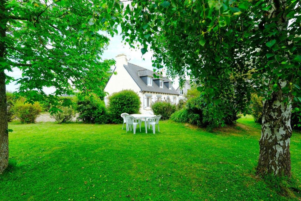 une table avec des chaises blanches dans la cour d'une maison dans l'établissement Gite Entre Mer Et Golf, à Plourhan