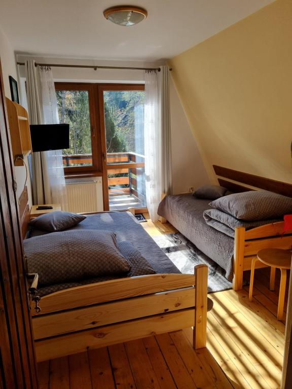 deux lits dans une chambre avec une fenêtre dans l'établissement Kwatery u Janka, à Zakopane