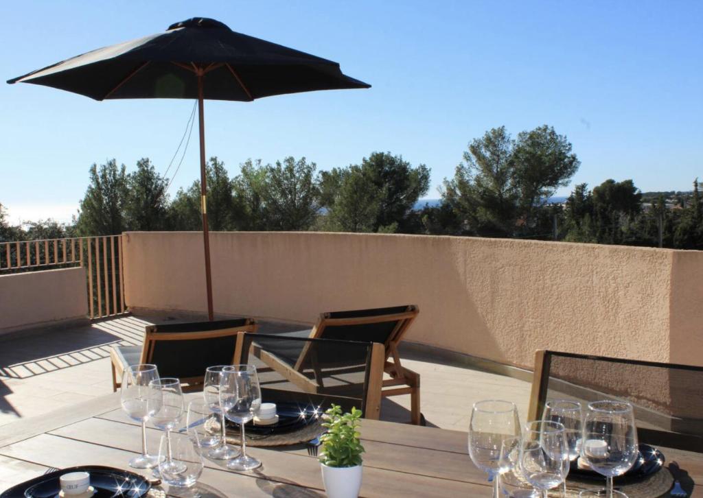 a table with glasses and an umbrella on a patio at Rooftop Privé Plein Soleil Mer Plage Port in Bandol