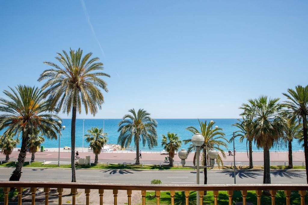 une vue sur une plage avec des palmiers et l'océan dans l'établissement Palais D'orient, à Nice