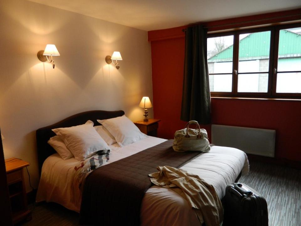 a bedroom with a large bed with a bag on it at LOGIS - Auberge Du Colombier in Guînes