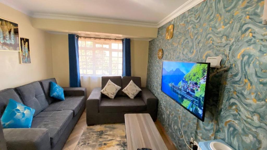 a living room with a couch and a tv on a wall at Lowell Stays in Nairobi