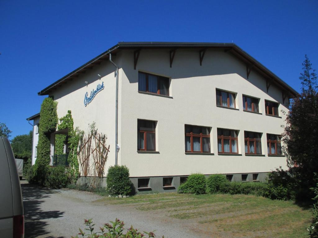 ein großes weißes Gebäude mit schwarzem Dach in der Unterkunft Pension Boddenblick in Bresewitz